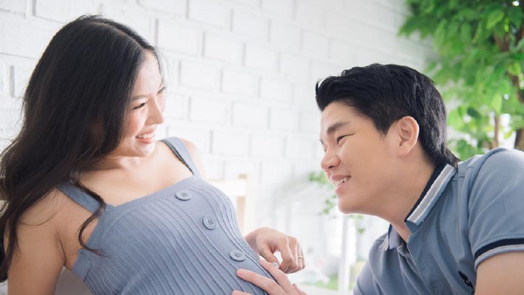 Happy pregnant woman with her husband in the room.