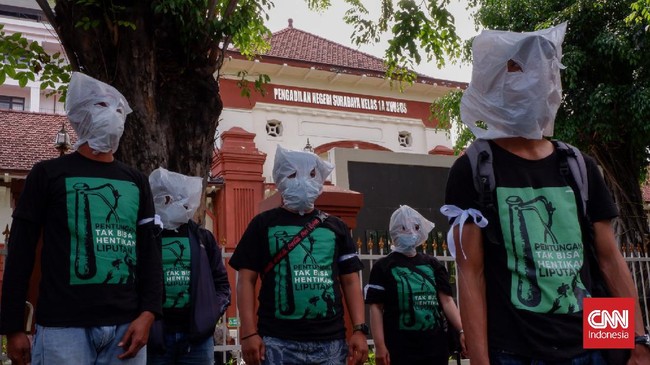 Pewarta berdemo dengan memakai tutup kepala dari kresek di depan PN Surabaya menuntut penanganan kasus penganiayaan jurnalis Tempo secara transparan.