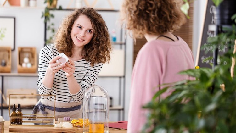 Young seller showing an organic skin product to a customer