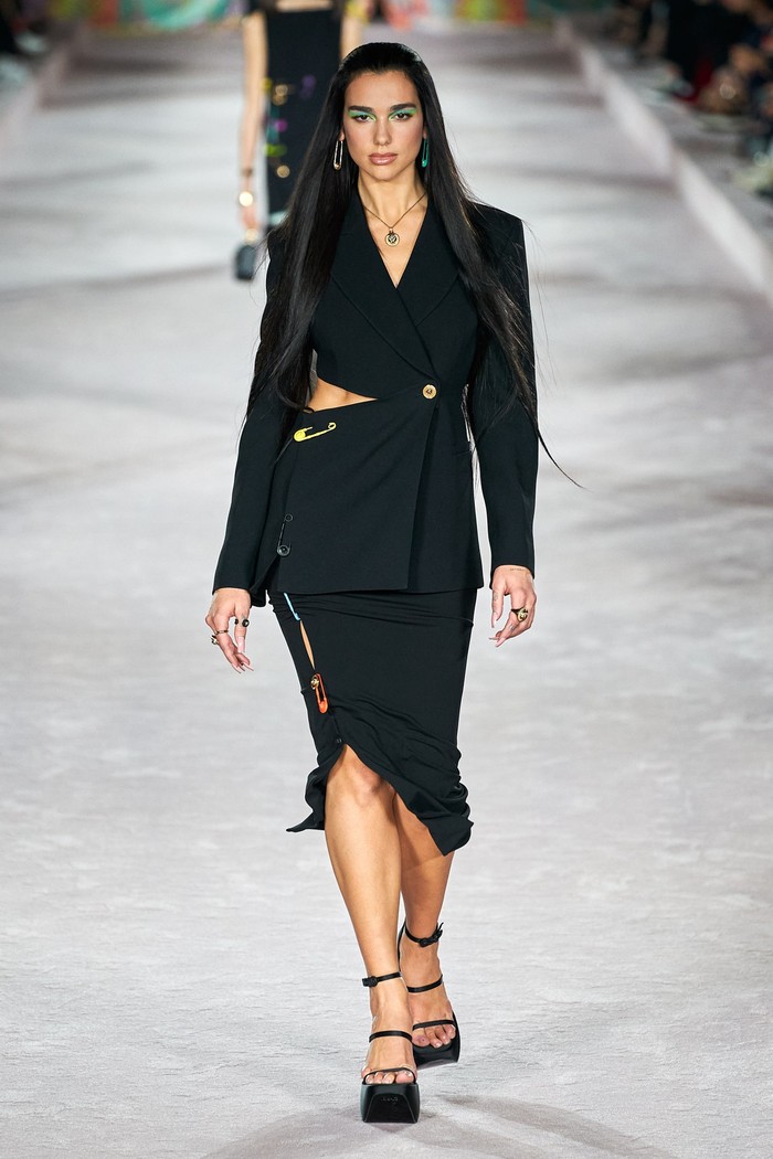 Dua Lipa opened the show by wearing a skirt suit with cut out accents and a pin on the skirt.  Photo: Alessandro Lucioni/Go Runway/Vogue