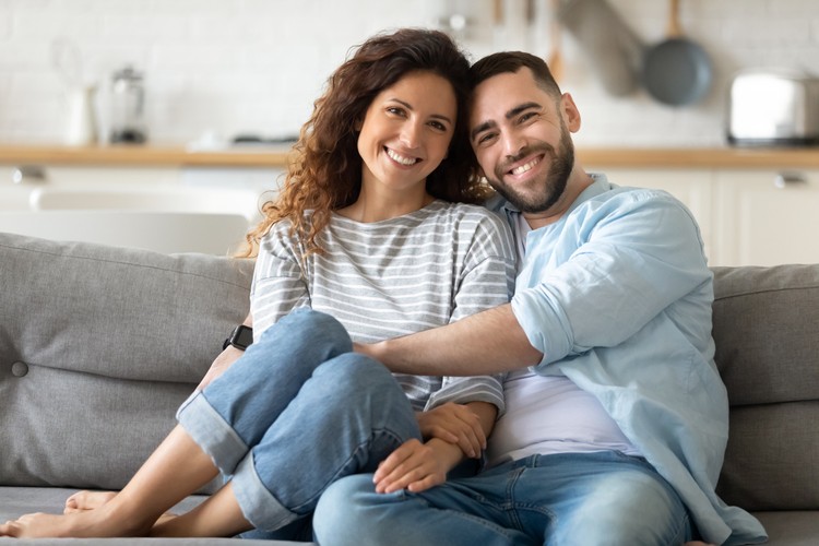 1198401599 Portrait of young 35s just married couple in love posing photo shooting seated on couch in modern studio apartments, concept of capture happy moment, harmonic relationships, care and sincere feelings