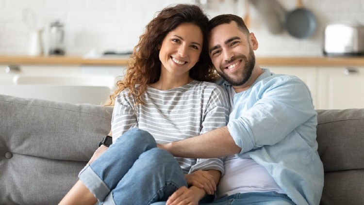 1198401599 Portrait of young 35s just married couple in love posing photo shooting seated on couch in modern studio apartments, concept of capture happy moment, harmonic relationships, care and sincere feelings