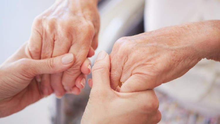 Closeup of a nurse holding an elderly woman's hands