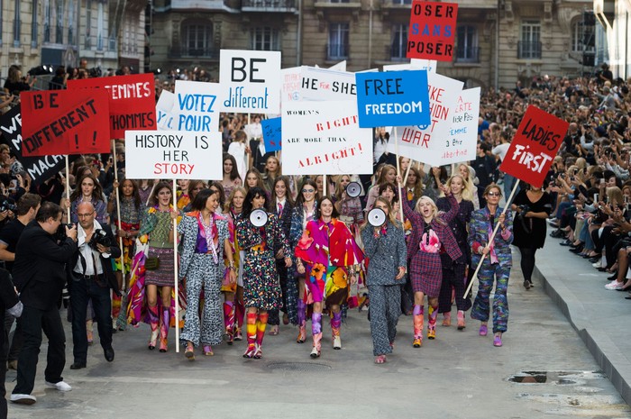 Secara mengejutkan dalam panggung berupa jalanan kota Paris untuk koleksi spring/summer 2015 ditutup dengan para model yang berakting melakukan demonstrasi. Foto: livingly.com/IMAXtree