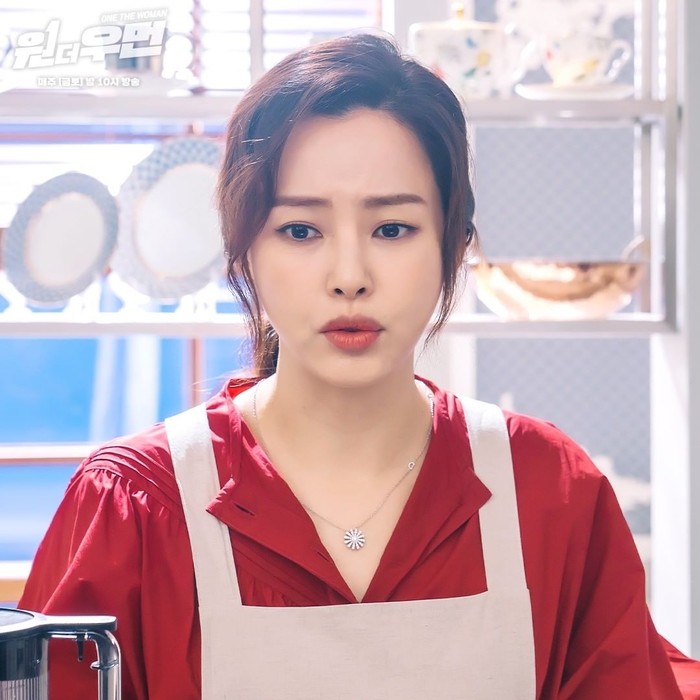 Gaya fashion Honey Lee saat di dapur pun juga terlihat stylish. Dengan rambut ala kucir kuda, ia memakai celemek yang dipadukan dengan kemeja satin merah yang cantik. Gayanya sebagai menantu di keluarga chaebol memang beda!/Foto: instagram.com/sbsdrama.official/