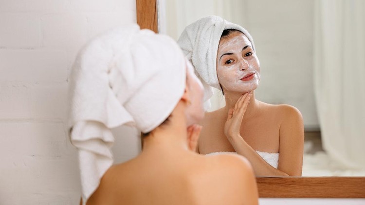 Beautiful woman having a facial cosmetic scrub treatment from professional dermatologist at wellness spa. Anti-aging, facial skin care and luxury lifestyle concept.