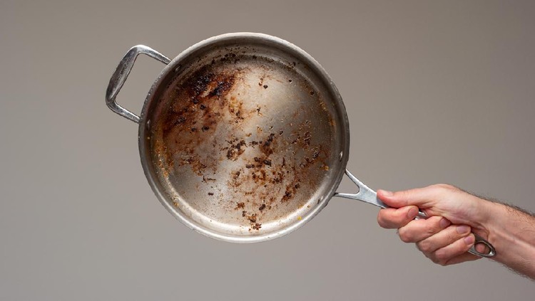 Ilustrasi Bersihkan Panci Gosong Dirty oily burnt metal frying pan held in hand by male hand. .
