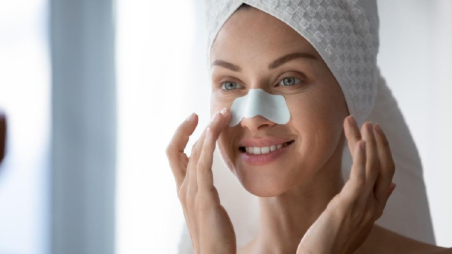 Close up 30s woman after shower with towel on head use white cleansing nose strips deep purifying treatment to unclog pores prevent remove blackheads, leaving skin clear and smooth, skincare concept