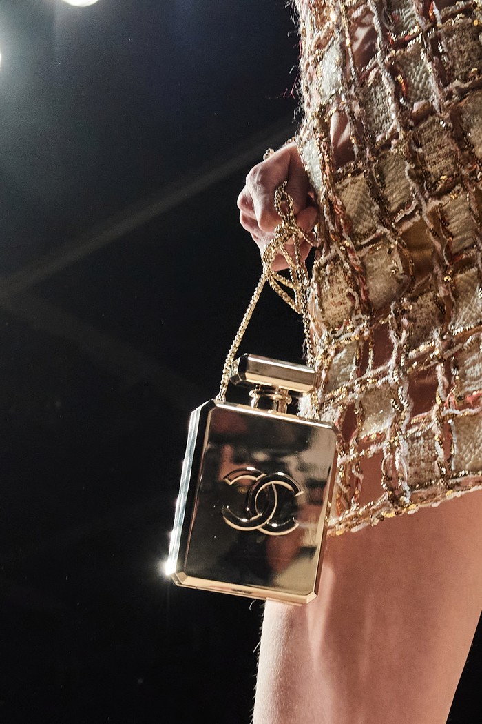 Peragaan busana dari Chanel menampilkan inspirasi tahun 90an dengan sentuhan modern. Begitu juga dengan aksesori tas mini yang dipresentasikan, seperti tas bentuk botol parfum emas ini. Foto: vogue.com