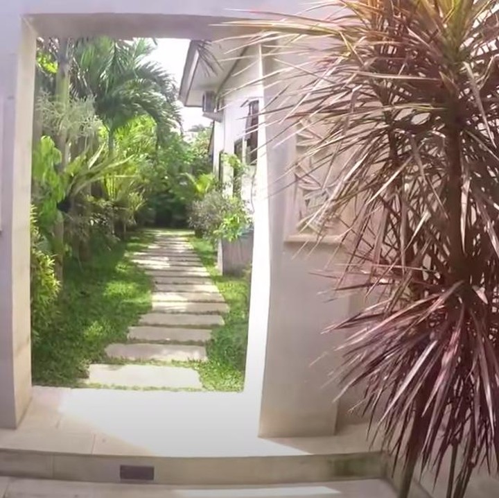 <p>Rumah Eks TKW Banyuwangi ini tampak asri. Ada pintu dan jalan setapak yang menghubungkan halaman depan rumah menuju ke halaman belakang rumah. (Foto: Youtube BAJIDOT VLOG)</p>