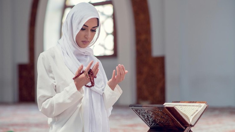 Ilustrasi wanita berhijab membaca Al Quran Young beautiful Muslim Woman Praying In Mosque.