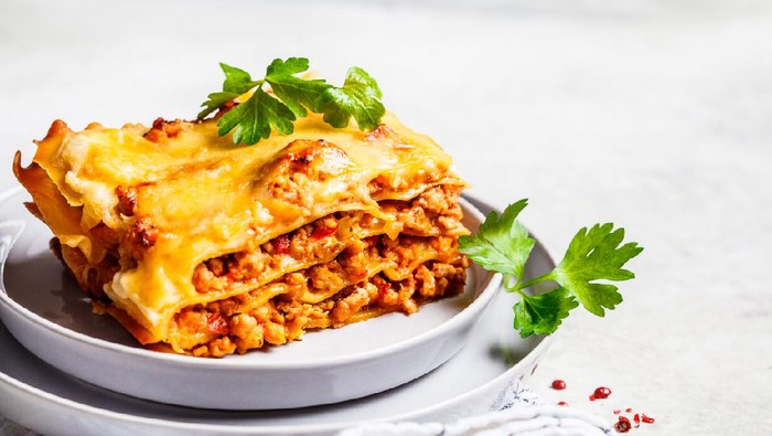 Close-up of classic meat lasagna with cheese on a gray plate. Italian food concept.