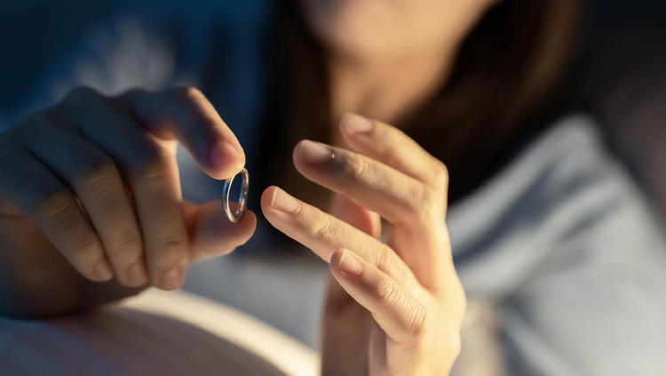 Divorce concept - close up of asian sad depressed woman taking off her wedding ring on the bed