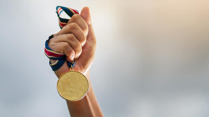 Hand holding gold medal on sky background, The winner and successful concept