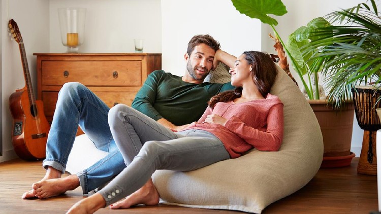 Shot of a smiling young couple talking together while relaxing on a beanbag sofa at home