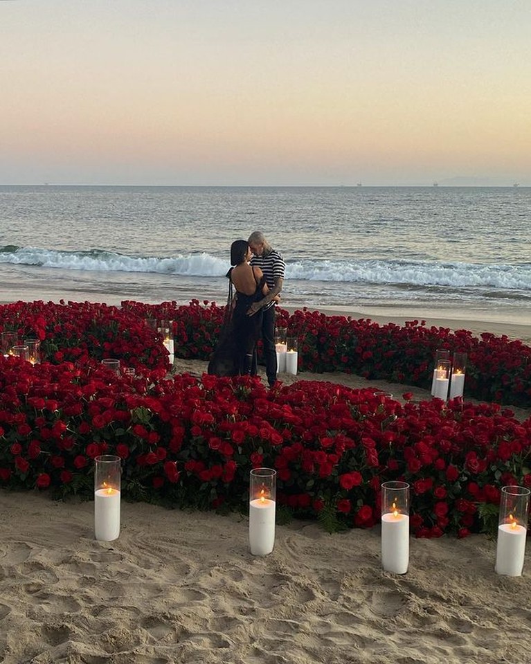 Travis Barker melamar Kourtney Kardashian dengan cara romantis di tepi pantai penuh bunga mawar. Yuk intip!
