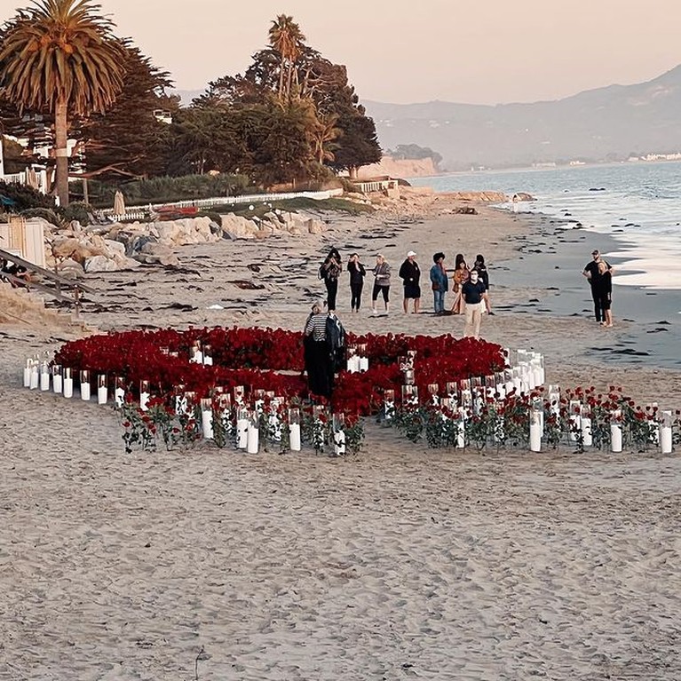 Travis Barker melamar Kourtney Kardashian dengan cara romantis di tepi pantai penuh bunga mawar. Yuk intip!