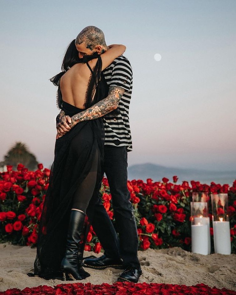 Travis Barker melamar Kourtney Kardashian dengan cara romantis di tepi pantai penuh bunga mawar. Yuk intip!
