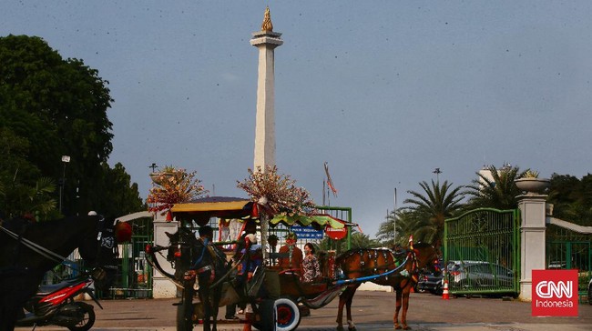 Area dalam Monas tetap tertutup bagi warga. Para warga yang datang hanya dapat berfoto ria di luar pagar Monas.
