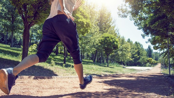 Low angle shot of a running woman on a path in the park - Healthy lifestyle
