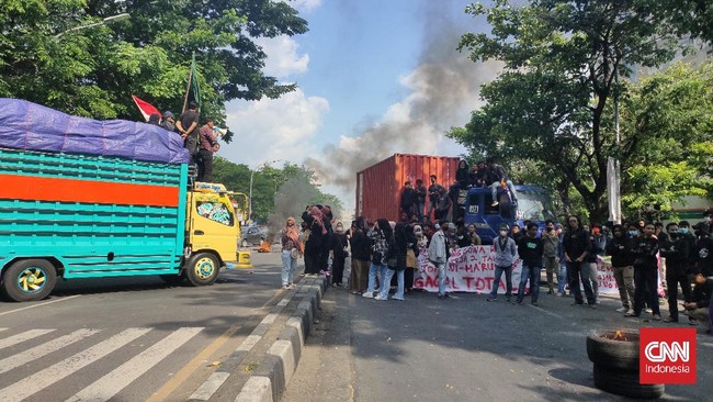 Mahasiswa melakukan pemblokiran dengan menahan dua truk dan membakar ban di Jalan Sultan Alauddin, Makassar.