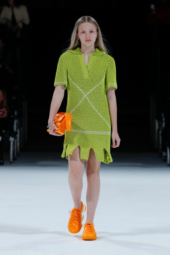 Nuansa kasual hadir lewat polo dress yang dikenakan bersama sneakers dalam warna orange. Foto: Courtesy of Bottega Veneta