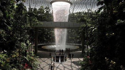 People walk past an indoor waterfall at Jewel Changi Airport in Singapore October 7, 2021. REUTERS/Edgar Su