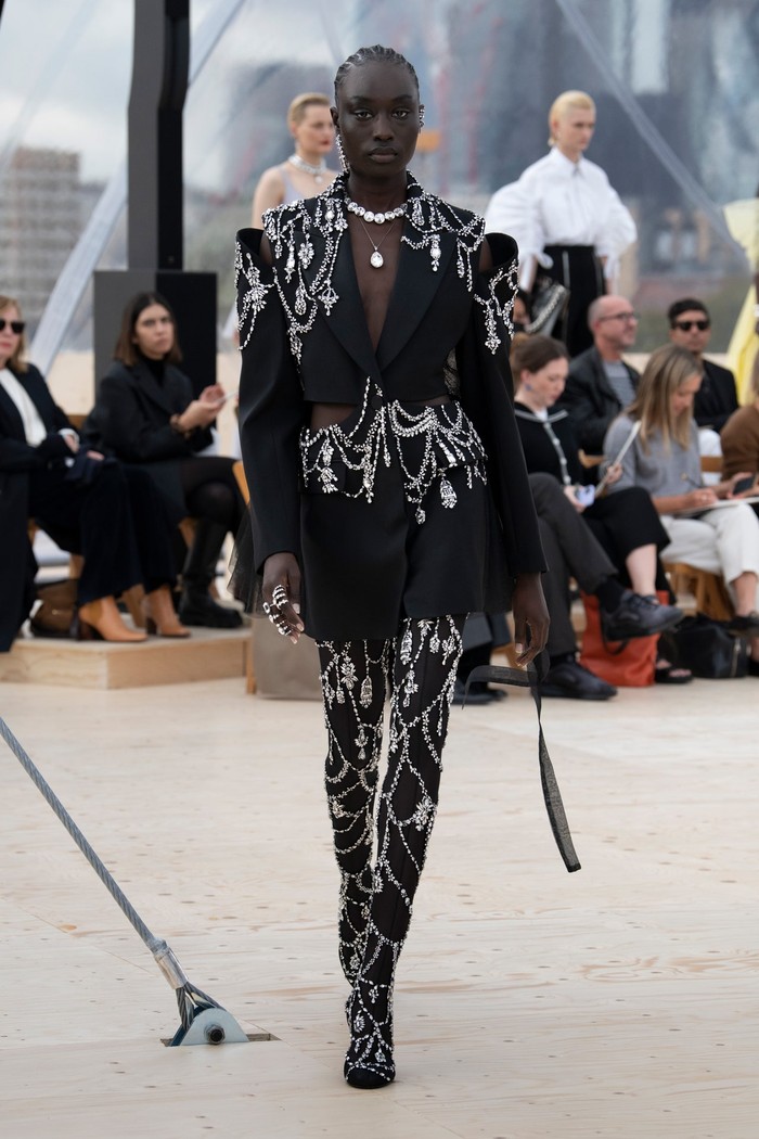 Sebuah blazer bertransformasi menjadi sebuah dress berkat detail embellishment yang mewah dan padanan stocking senada. Foto: Courtesy of Alexander McQueen