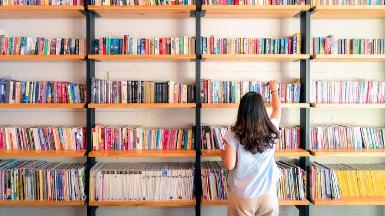 ilustrasi menata rak buku Asian women are picking up books on the bookshelf. To prepare to back to school