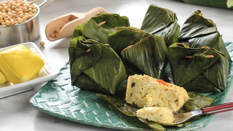 Pepes Tahu is Indonesian Spiced Tofu Wrapped with Banana Leaf and Steamed, Typically Indonesian Food from West Java (Sundanese). Steamed Tofu with Asian Basil, White Background