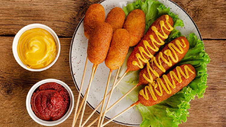 Deep fried corn dogs with mustard and ketchup on wooden background. American junk food concept. Top view