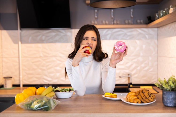 Dieting Concept. Young Woman Choosing Between Fruits And Sweets.