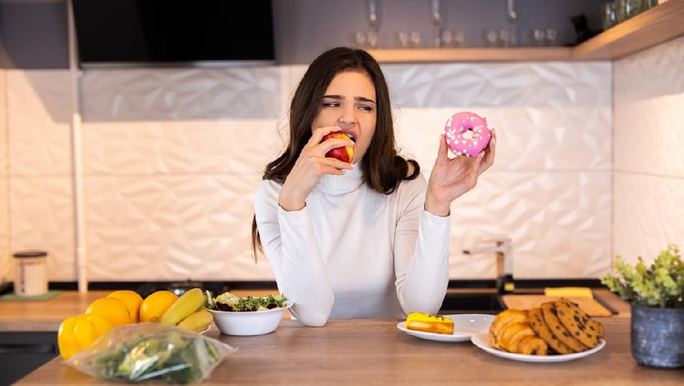 Dieting Concept. Young Woman Choosing Between Fruits And Sweets.
