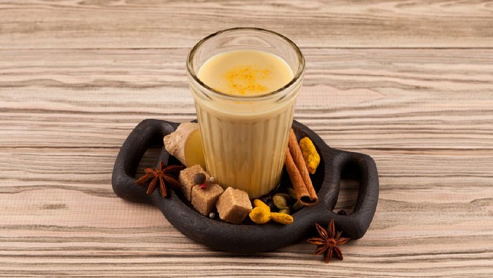 Bandrek- ginger tea in Indonesian. It is made from coconut milk or condensed milk and various spices. The drink is popular on the island of Java. Wooden background, selective focus.