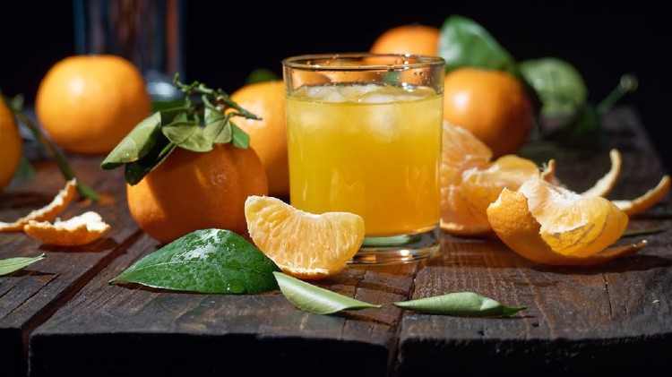 Tangerine juice in drinking glasses amid the tangerines lying on the table. Close-up