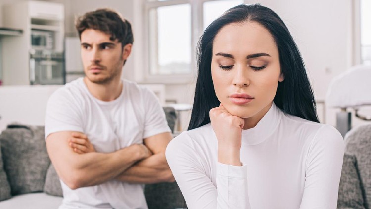 sad offended couple sitting on sofa after argument during self isolation at home