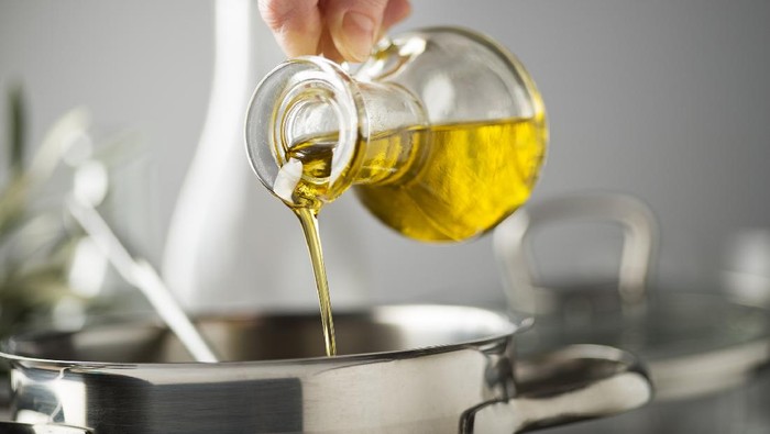 Cooking meal in a pot. Bottle of Extra virgin oil pouring in to pot for cooking meal. Healthy food concept.