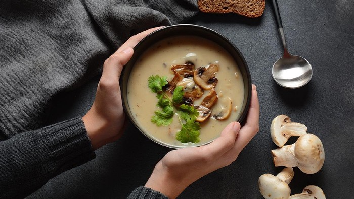 A bowl of Mushroom Cream Soup with fried champignons and fresh parsley. Winter, autumn hot soup concept