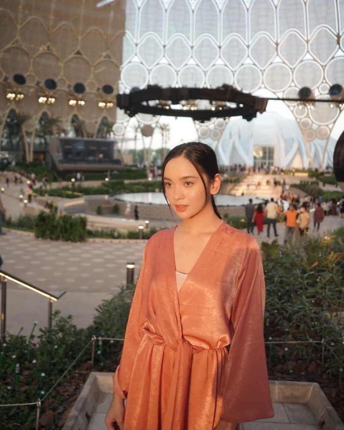 Lyodra tampak memukau saat mengunjungi Dubai Exhibition Centre dalam balutan satin playsuit merah muda koleksi Zara. Penampilannya terlihat semakin cantik ketika dipadukan dengan riasan tipis. (Foto: Instagram.com/lyodraofficial)