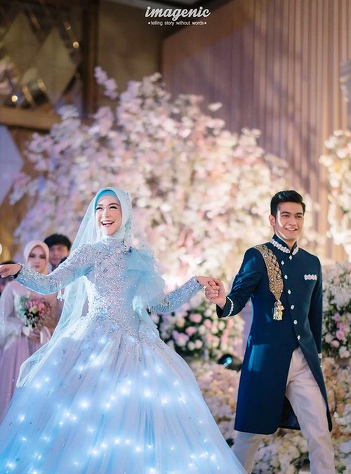 Pemilik nama Ria Yunita ini tampil cantik mengenakan gaun berwarna biru cerah rancangan Lisa Ju, seorang fashion designer dari Bandung. Istimewanya, gaun tersebut dapat mengeluarkan cahaya yang semakin menambah kesan indah dan mewah pada bagian rok bawahnya. (Foto: Instagram.com/riaricis1795/imagenic)