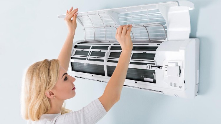 A Young Woman Cleaning Air Conditioning System At Home