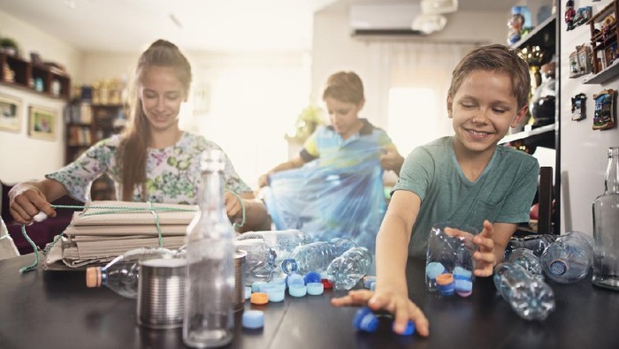 Three kids sorting garbage at home - plastic bottles, cans, glass bottles and cardboard.
Nikon D850