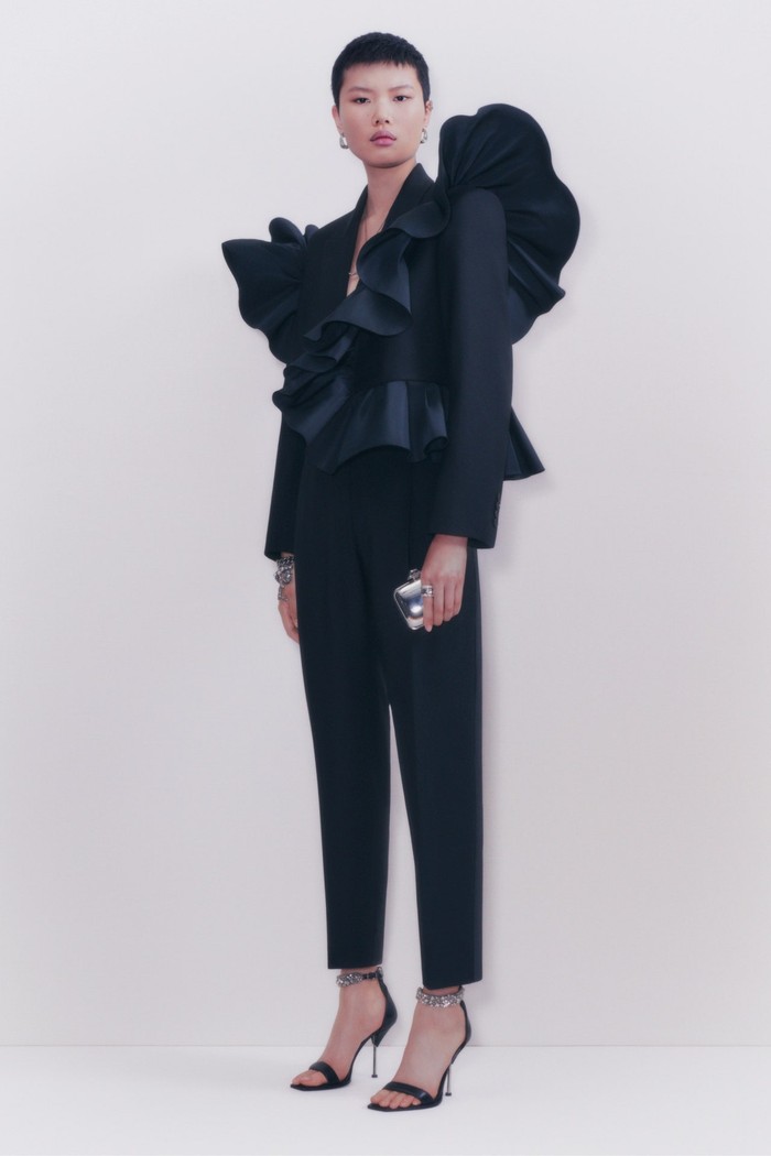 Setelan jas hitam memang dapat menjadi opsi sempurna sebagai pengganti gaun malam. Alexander McQueen kali ini menggubahnya dalam detail ruffles yang memenuhi bagian jaket. Foto: Chloe Le Drezen / Courtesy of Alexander McQueen