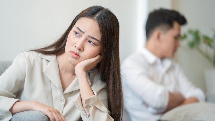 Young couple in quarrel at home.sadness young Asian woman sitting on sofa with boyfriends.relationship problems between couples and communication issues concept