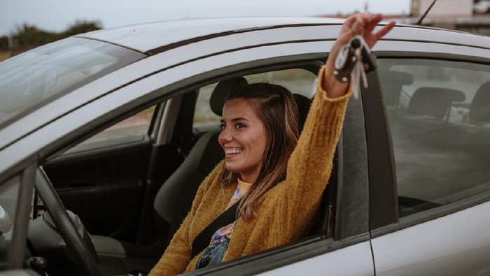 A young woman with a happy expression on her face, holding her new car keys