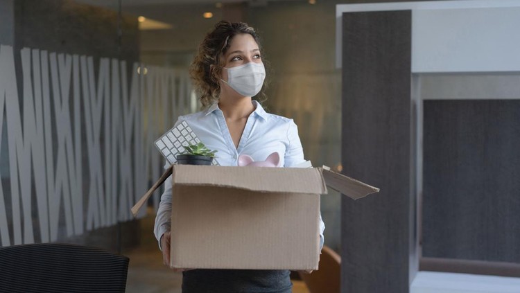 Ilustrasi Langkah Sebelum Resign Female worker wearing a facemask at the office while holding a box with her belongings after being fired from her job during the COVID-19 pandemic