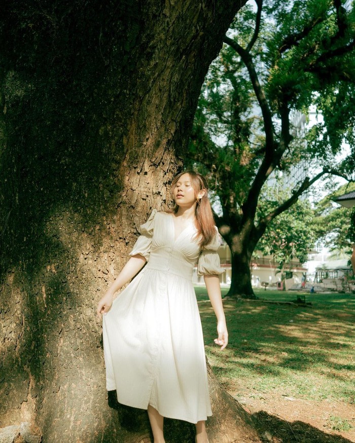 Berpose di bawah sinar mentari, Nadin tampil simpel namun memukau dengan midi dress putih yang membuatnya mirip tokoh Ibu Peri dari Negeri Dongeng (Foto: Instagram.com/cakecaine).