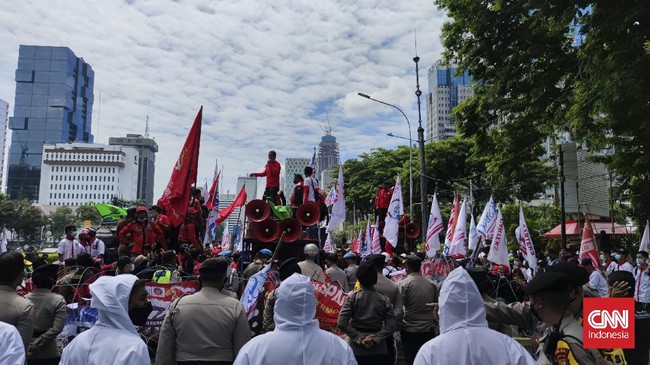 Ribuan peserta aksi dari berbagai serikat buruh memadati area Patung Kuda Arjuna Wijaya. Mereka berbaris di depan pagar duri yang dibentangkan aparat kepolisian.