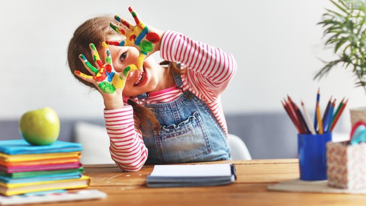 happy funny child girl draws laughing shows hands dirty with paint