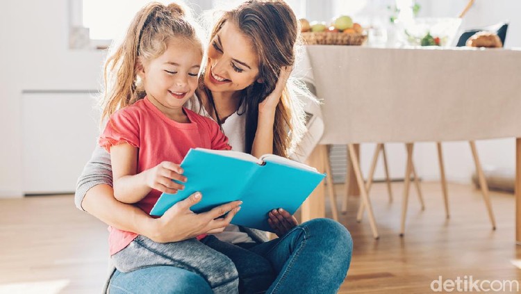 Mother and daughter reading book on the floor.